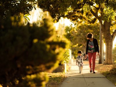 woman holding a child walking in the pathway