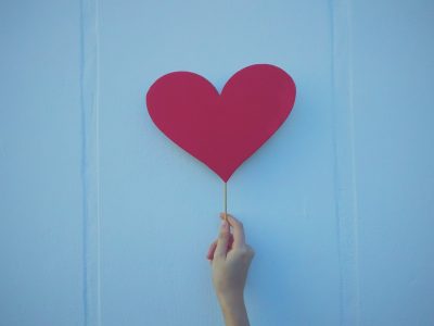 person holding heart shaped red balloon